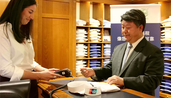 银联国际首席执行官蔡剑波(右)在moneris业务开通现场展示刷银联卡